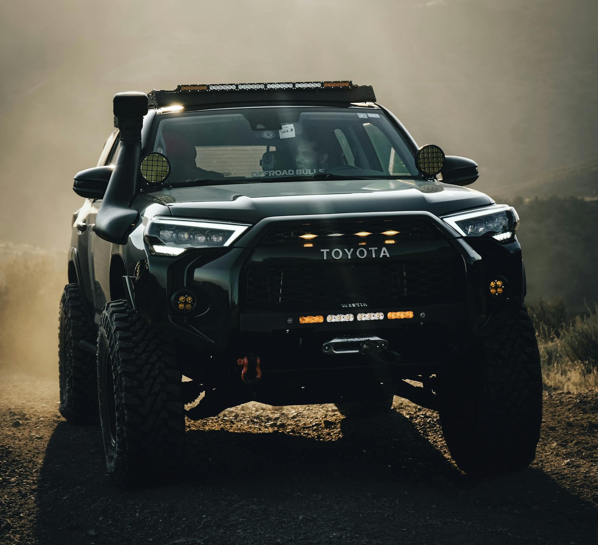 Powerful Toyota truck navigating rugged terrain in dusty conditions.